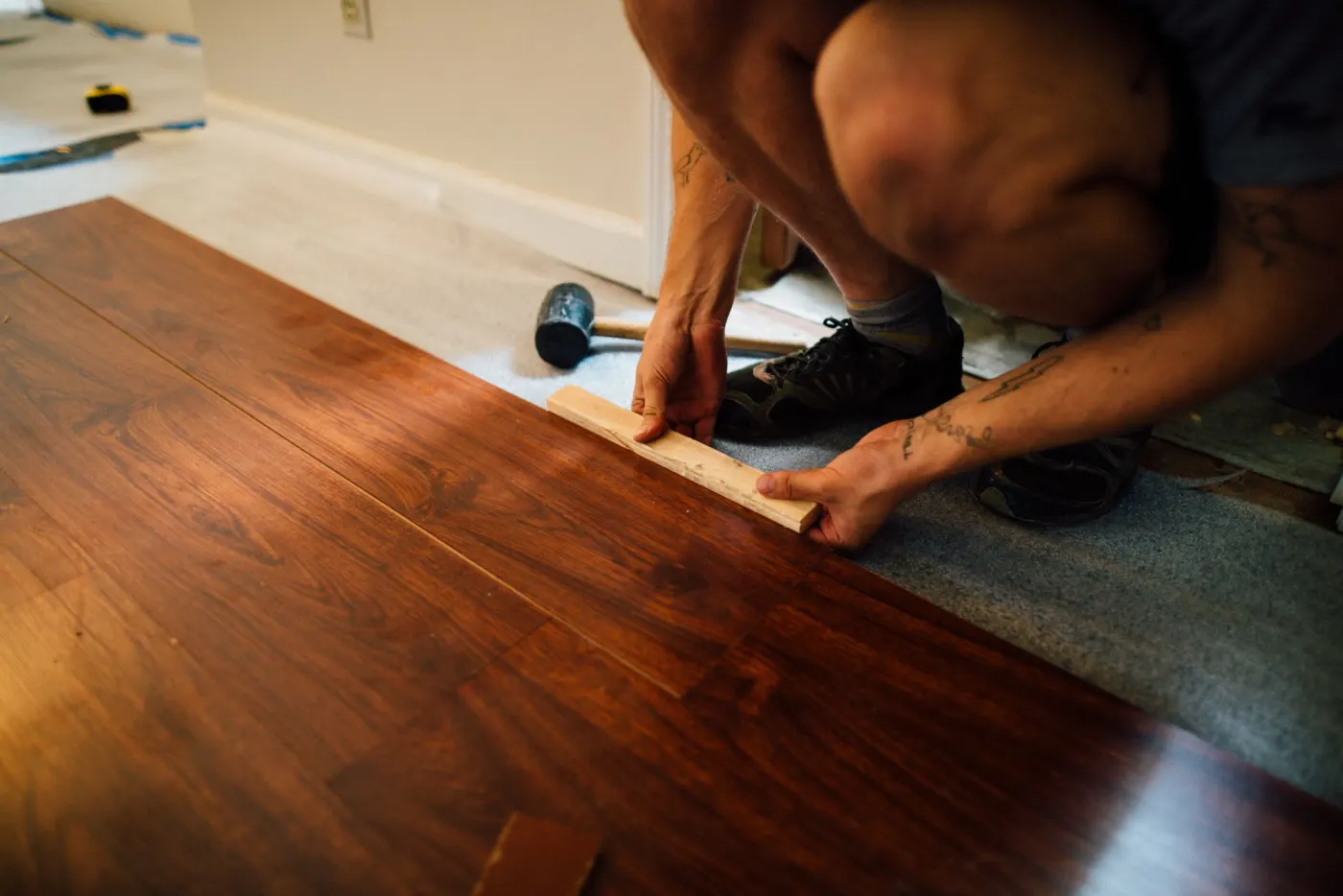 Hände verlegen Laminatdielen auf Trittschalldämmung