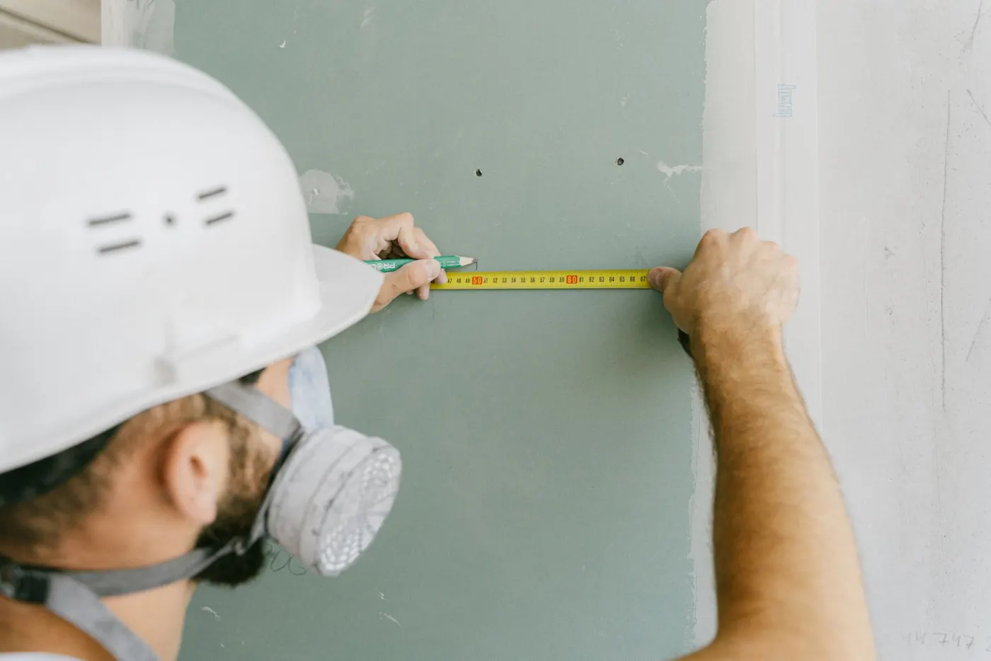 Handwerker prüft eine Gipskartonwand mit der Wasserwaage